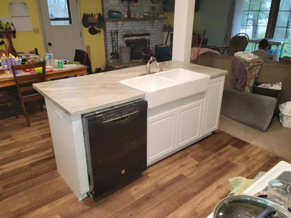 White kitchen island with farmhouse sink, wood countertop, and black dishwasher integration