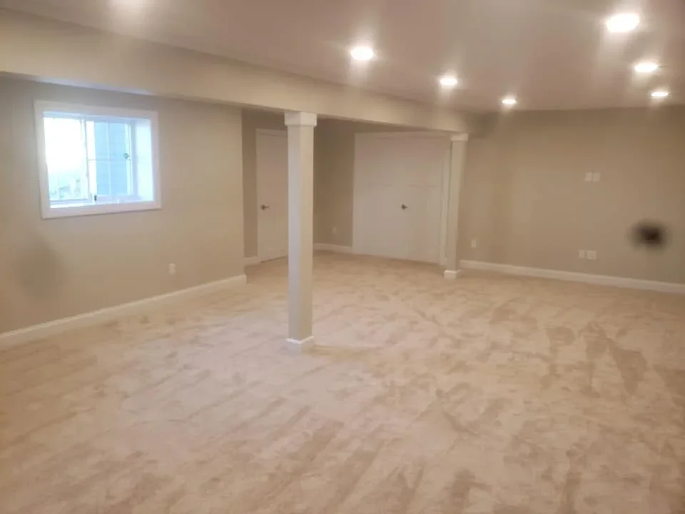 Finished basement with engineered hardwood flooring, support columns, and recessed lighting
