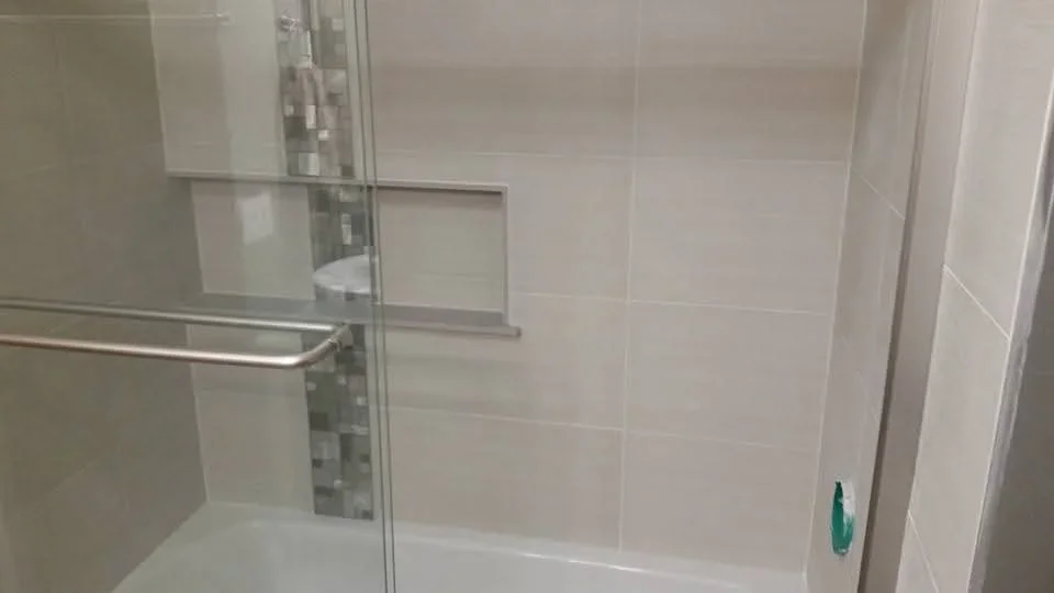 Frameless glass shower door with brushed nickel hardware and subway tile surround