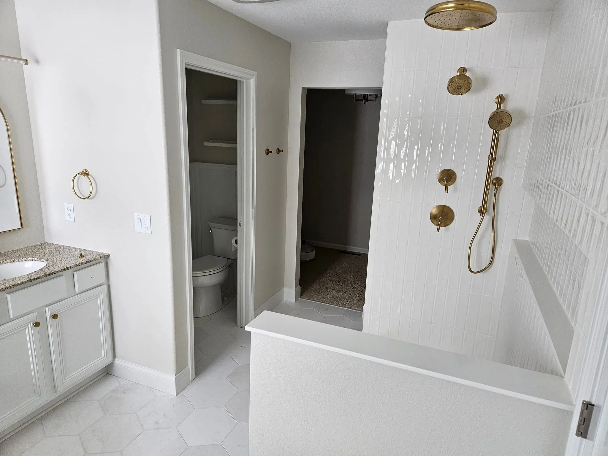 White subway tile bathroom with brass fixtures, granite vanity, and walk-in shower