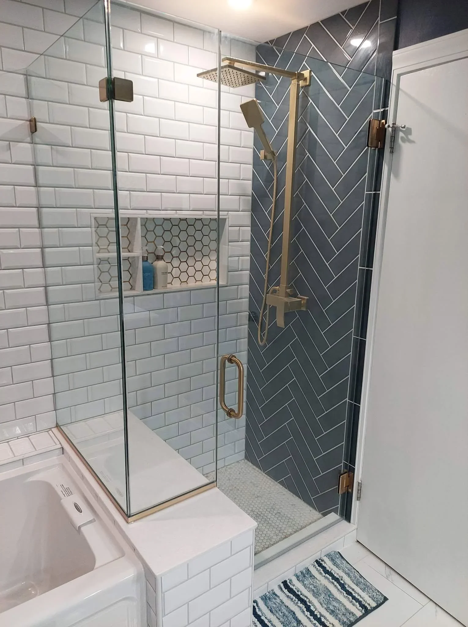 Walk-in shower with herringbone charcoal tile, white subway tile, and hexagonal floor mosaic