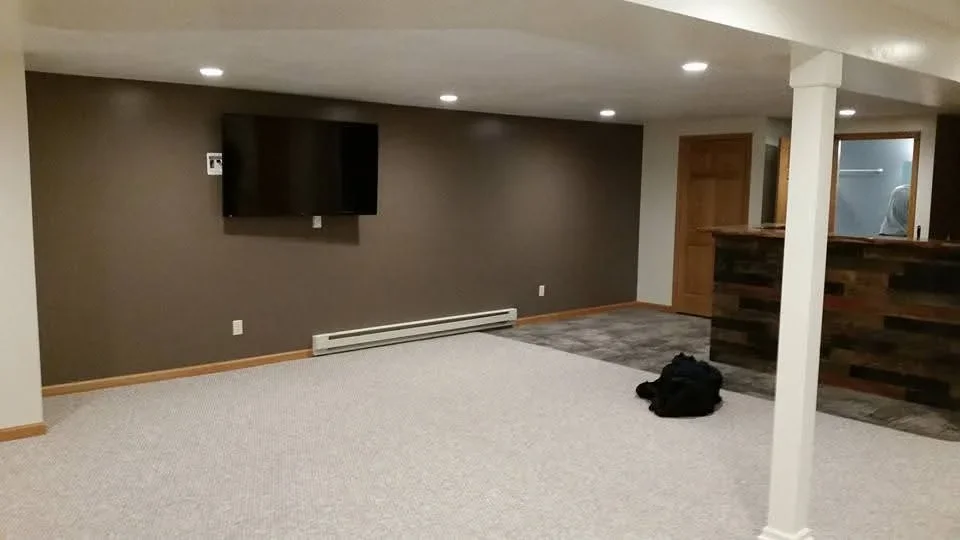 Finished basement with taupe drywall, recessed lights, carpet flooring, and TV mount