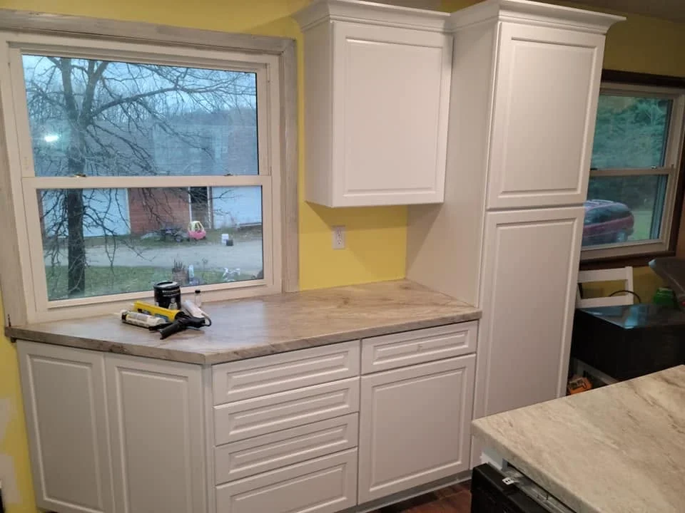 White shaker cabinets with gray quartz countertops and yellow accent wall in kitchen