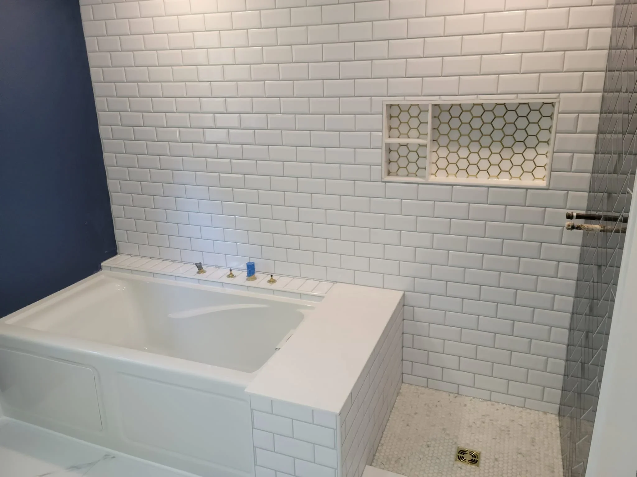 White subway tile bathroom with penny round mosaic accent, soaking tub, and stone floor