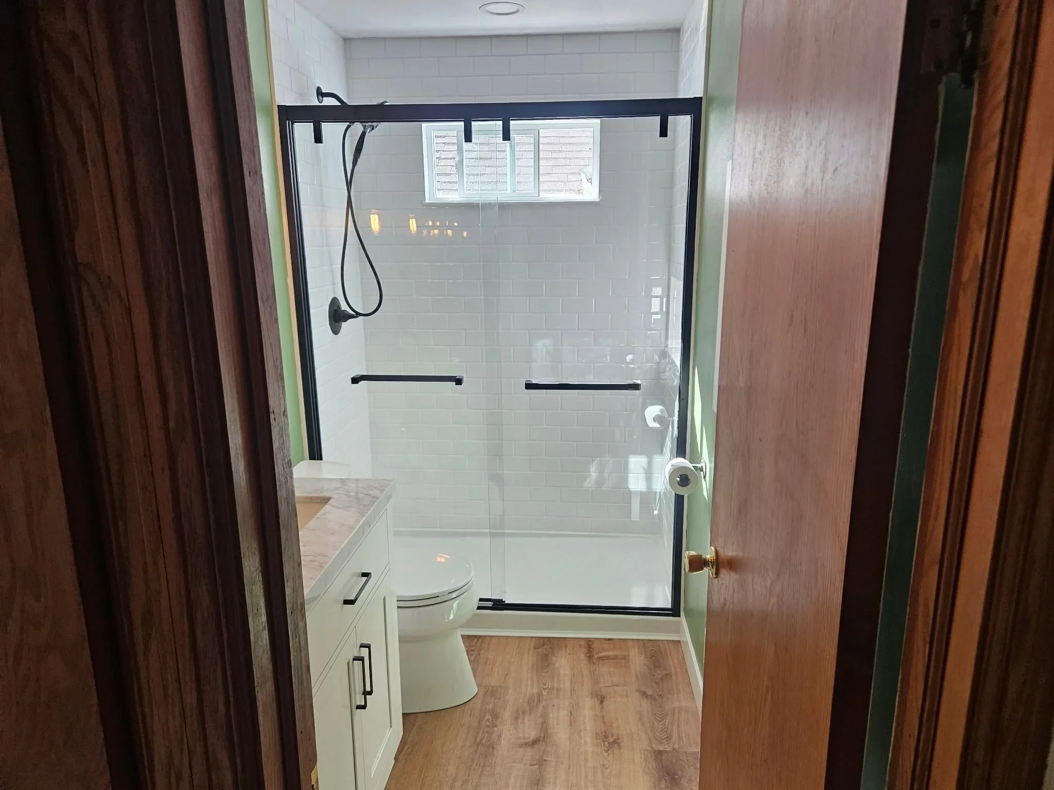 Frameless glass shower with black hardware, white subway tile, and black trim framing
