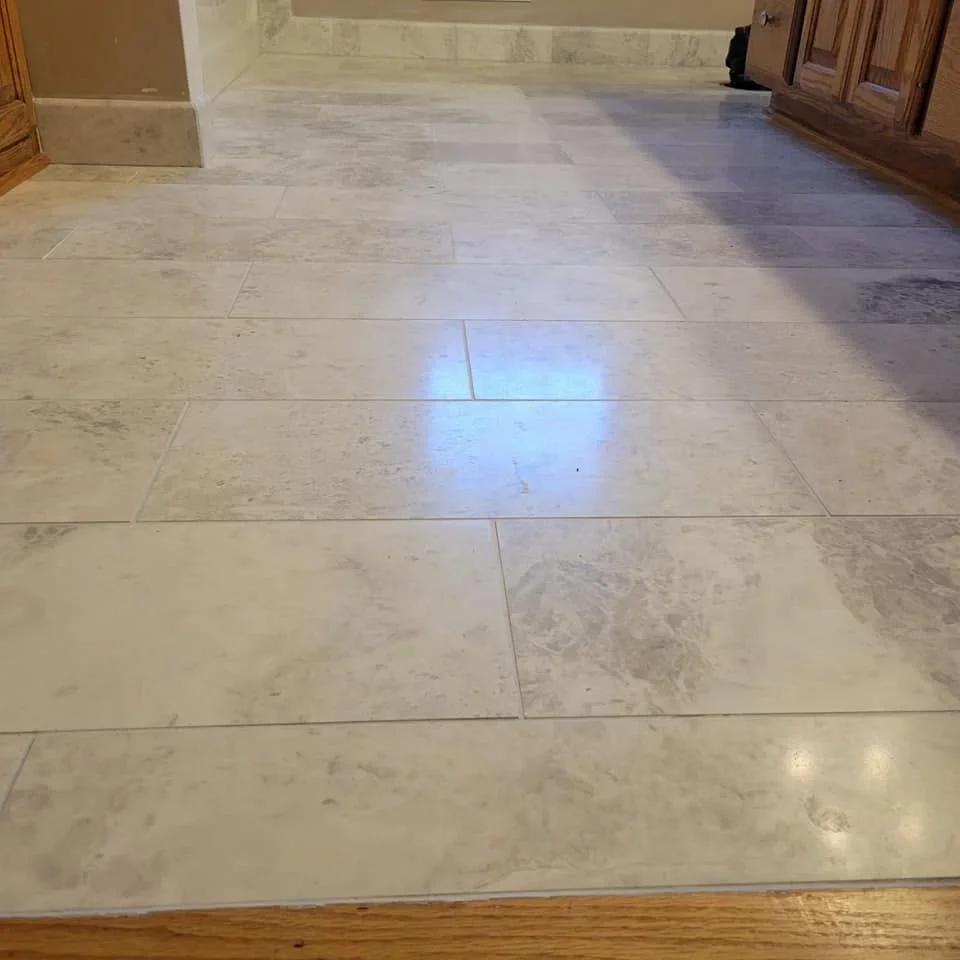 Light marble tile flooring with natural veining installed in rectangular pattern with grout lines
