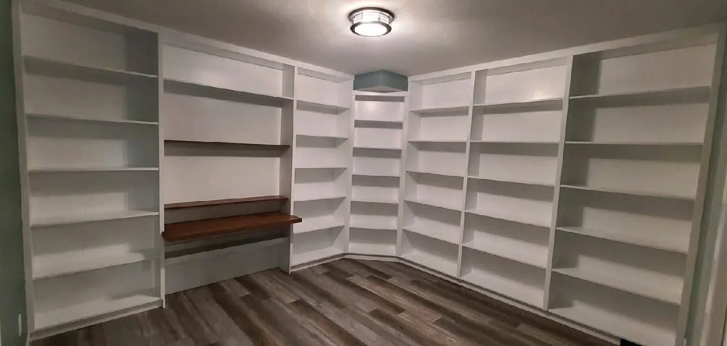 White built-in shelving with dark wood accent shelf and recessed lighting