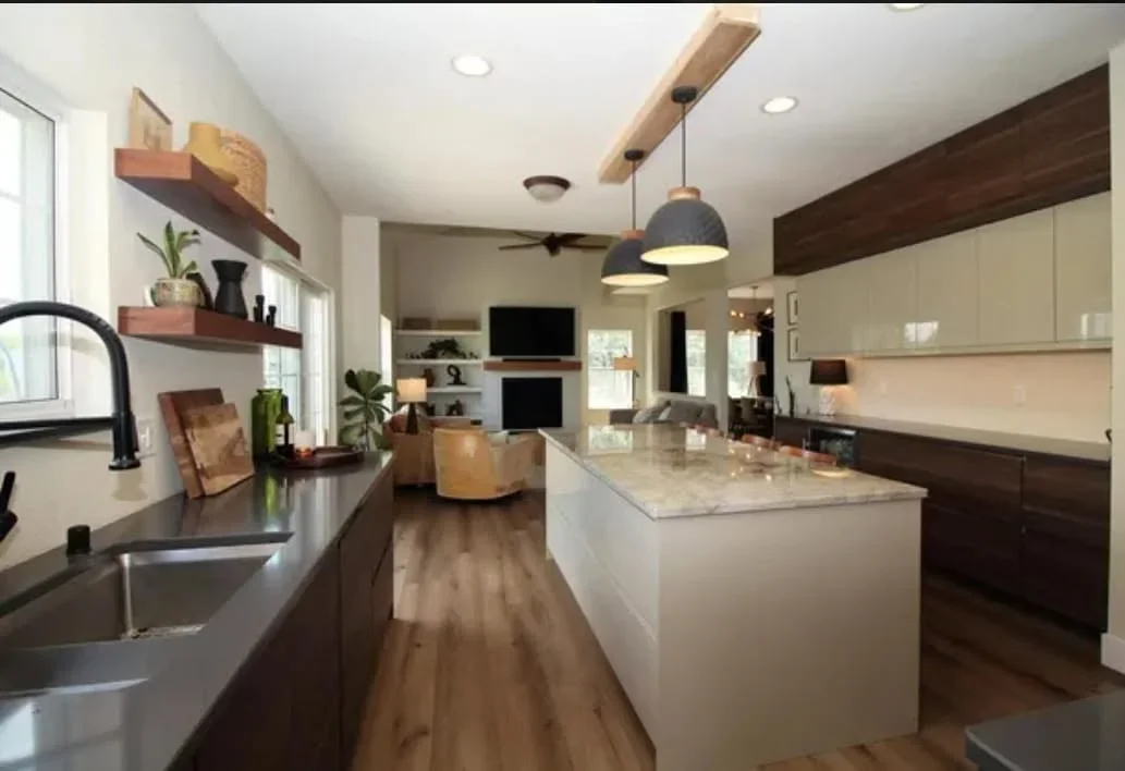 Modern kitchen with white island, dark and cream cabinetry, quartz countertops, hardwood floors