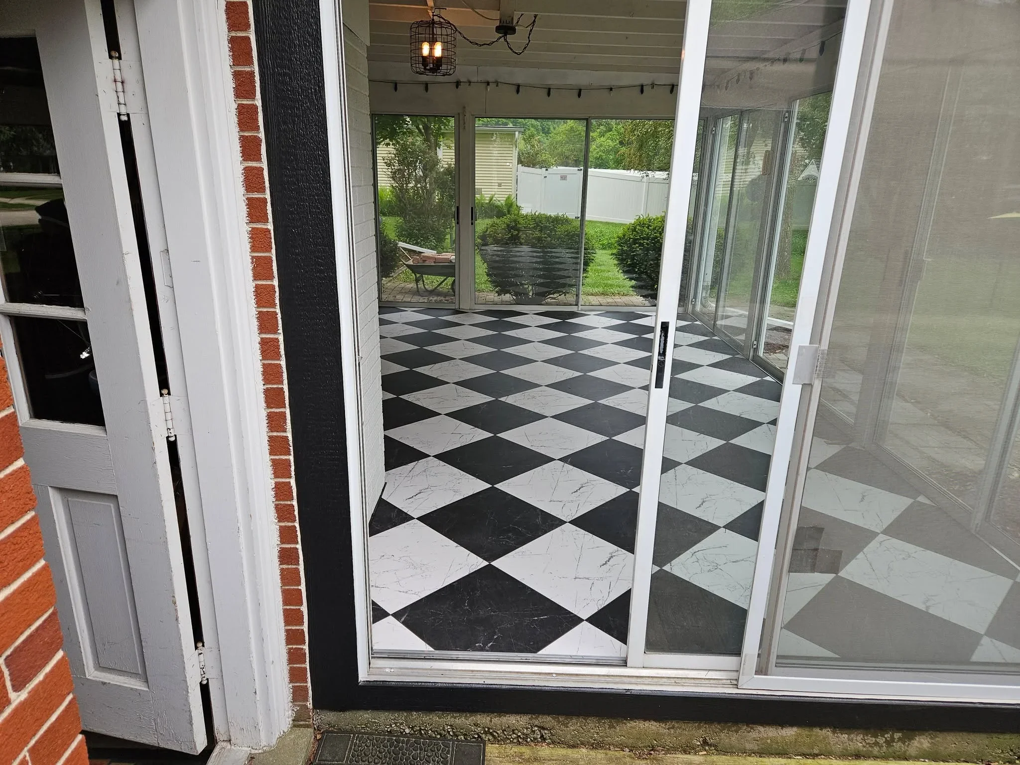 Black and white diamond pattern marble tile flooring in enclosed porch with glass doors