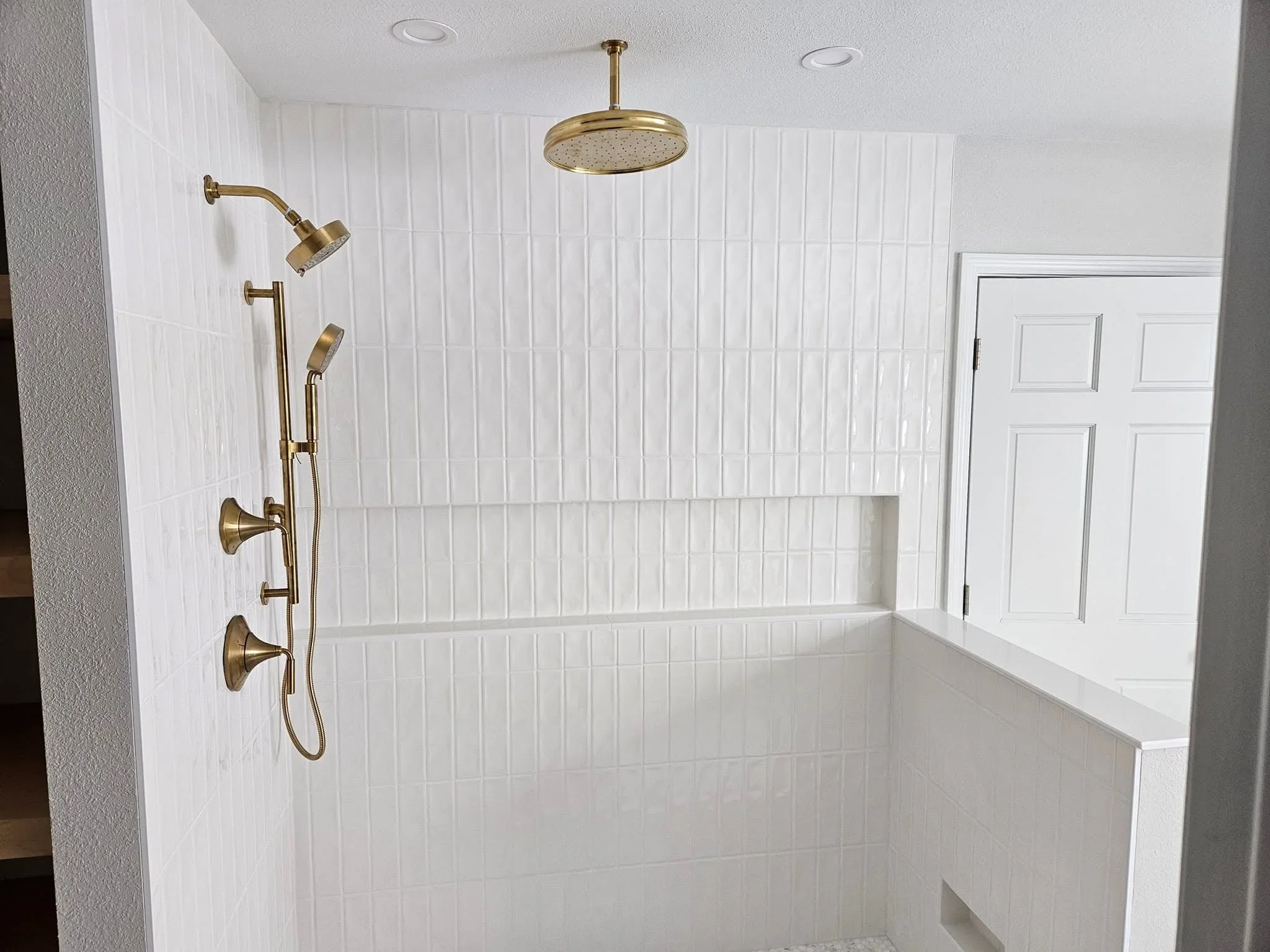 White subway tile shower with brass fixtures, rainfall showerhead, and soaking tub