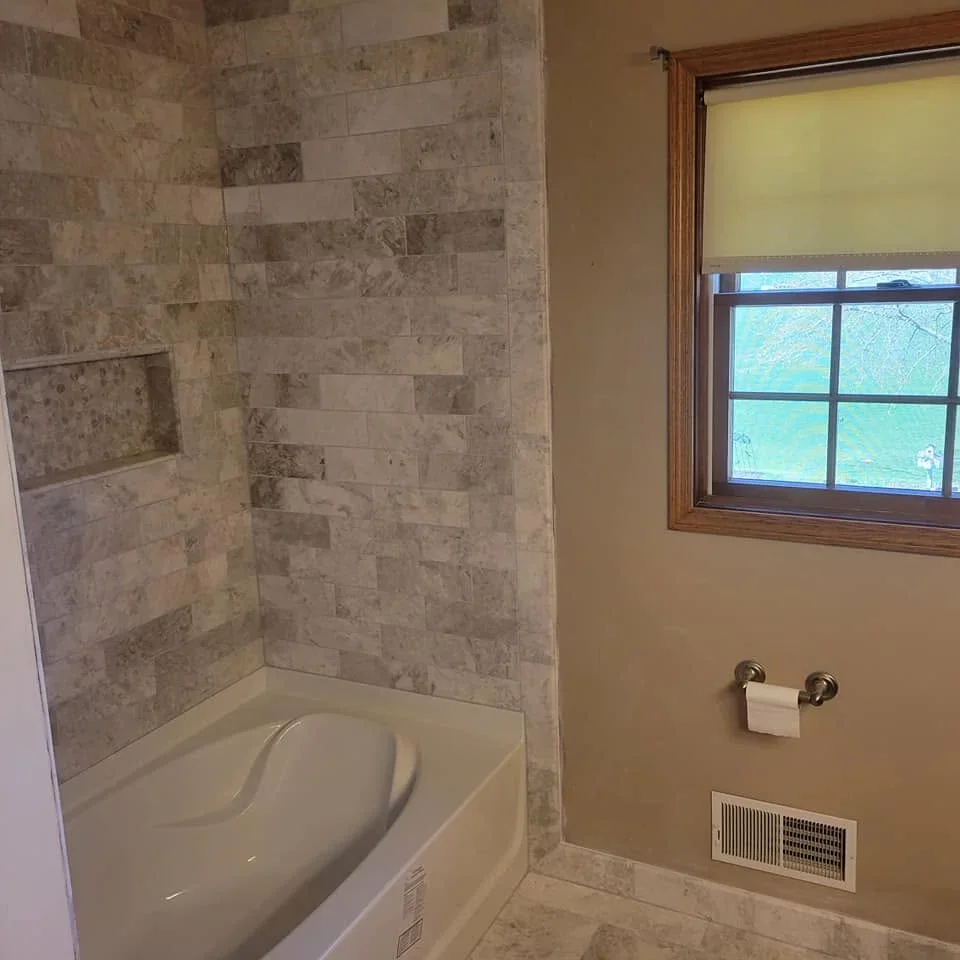 Travertine tile bathroom surround with staggered rectangular tiles and built-in soap niche