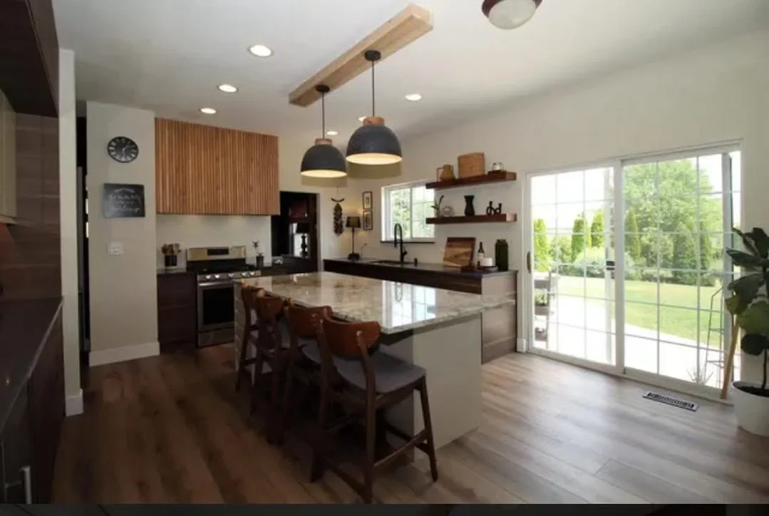 Kitchen with wood cabinets, quartz countertops, island, pendant lights, and stainless steel appliances