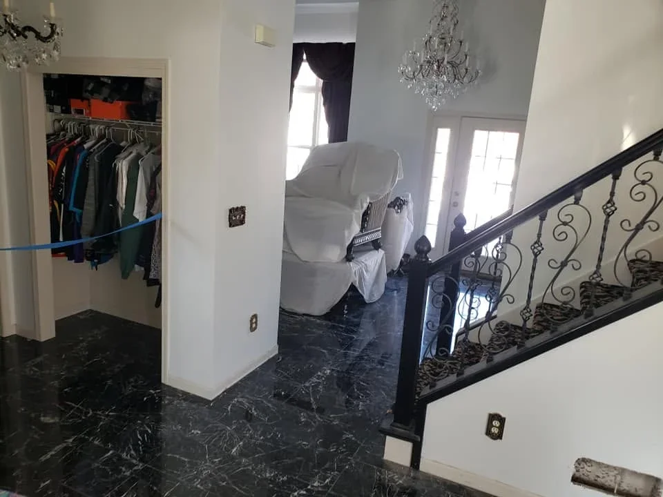 Black marble flooring in foyer with wrought iron staircase railing and white walls