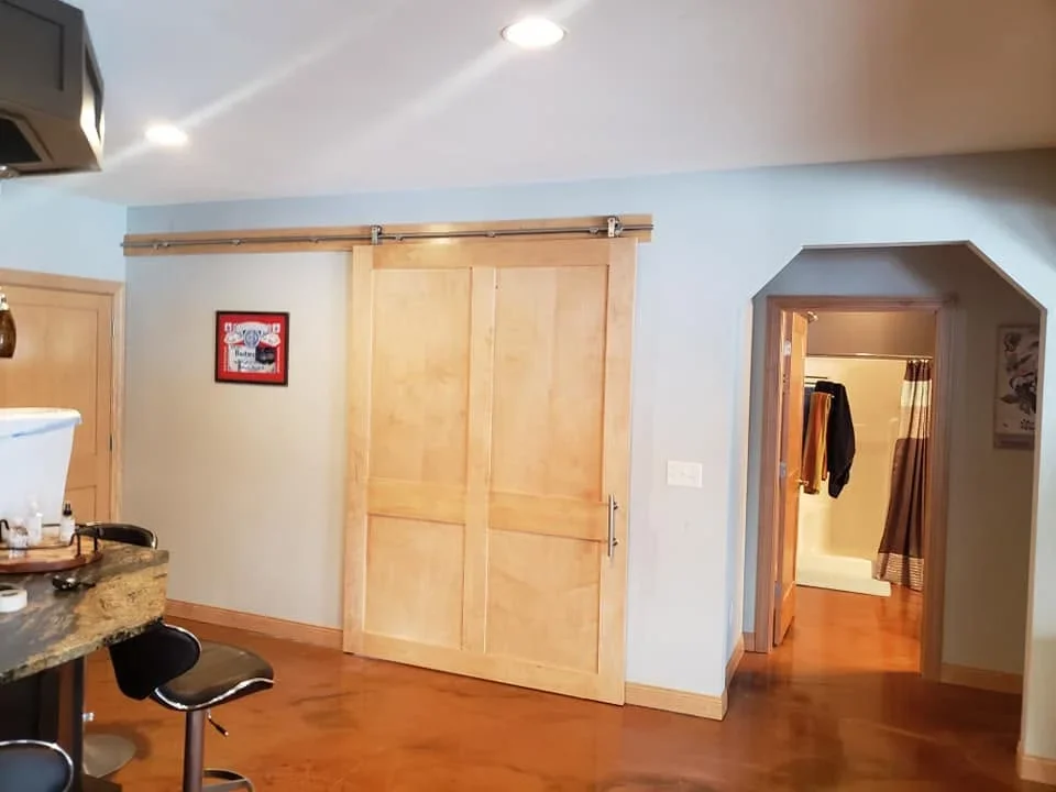 Natural wood barn doors with metal sliding track hardware installed in residential interior