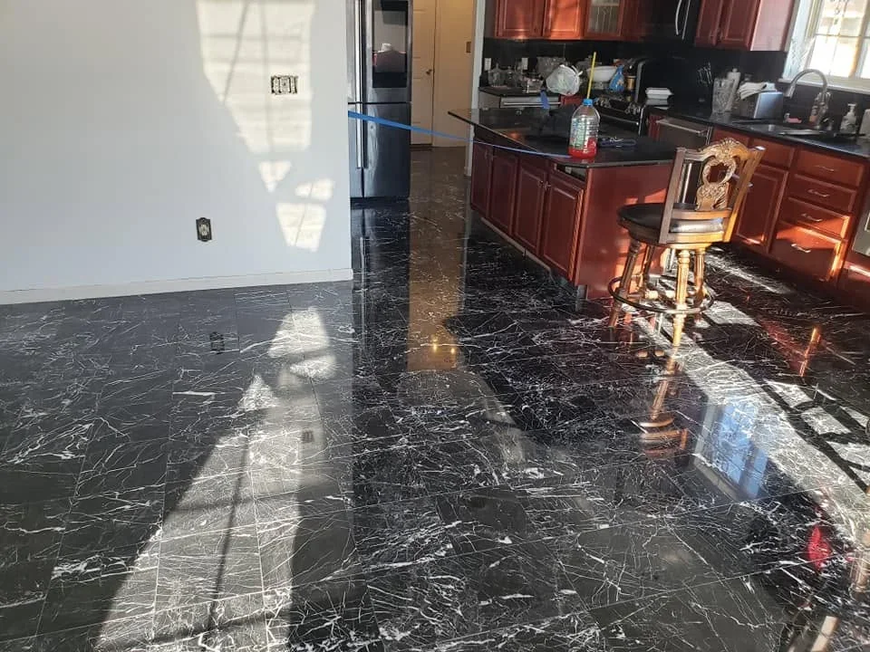 Black marble tile flooring with white veining installed in kitchen with cherry cabinets