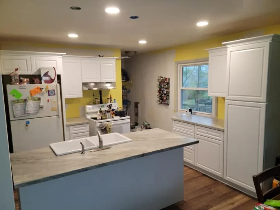White cabinetry kitchen with blue island, light wood counters, and recessed lighting