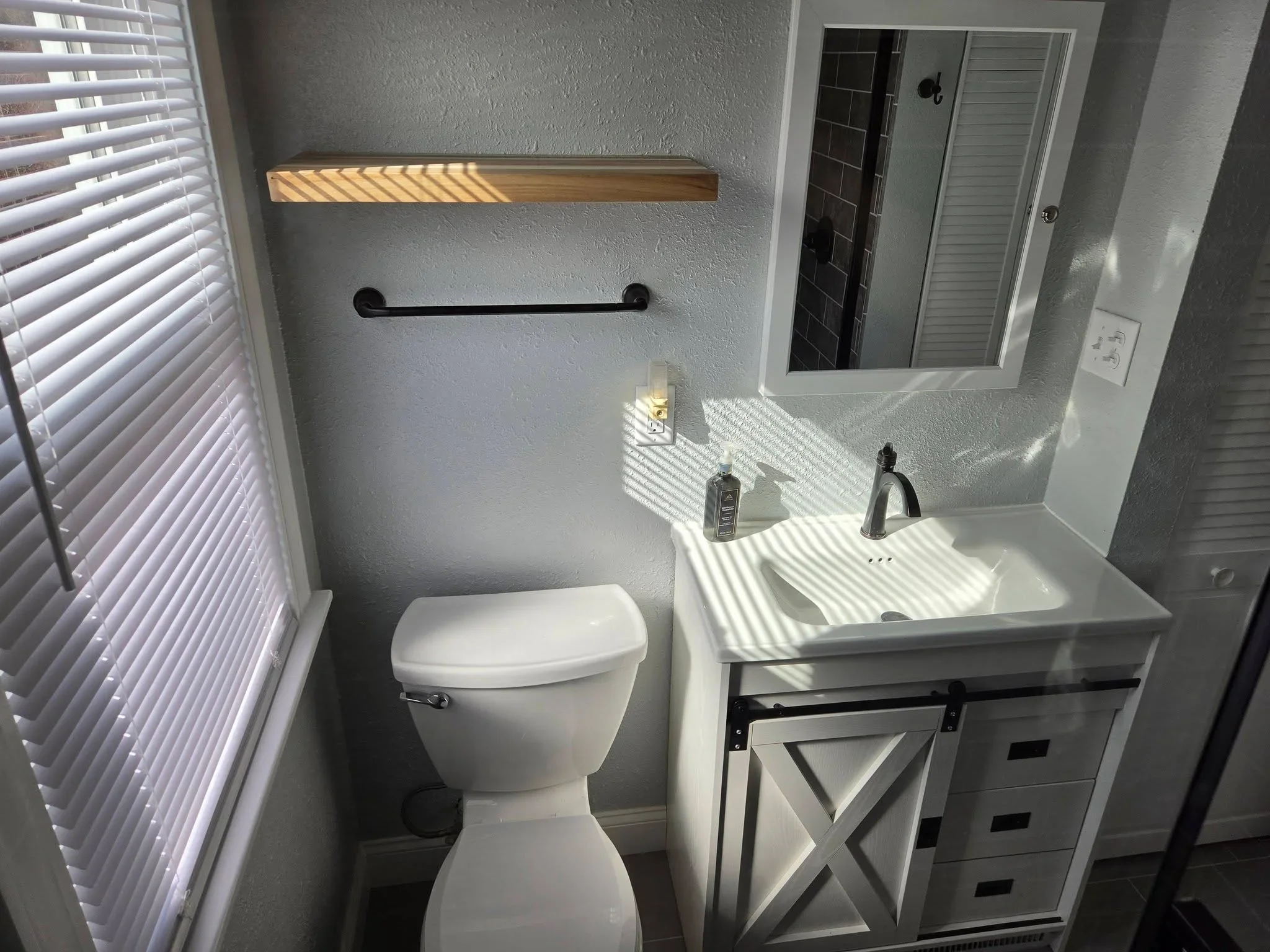 White vanity with barn door cabinet, quartz countertop, and oil-rubbed bronze faucet in bathroom
