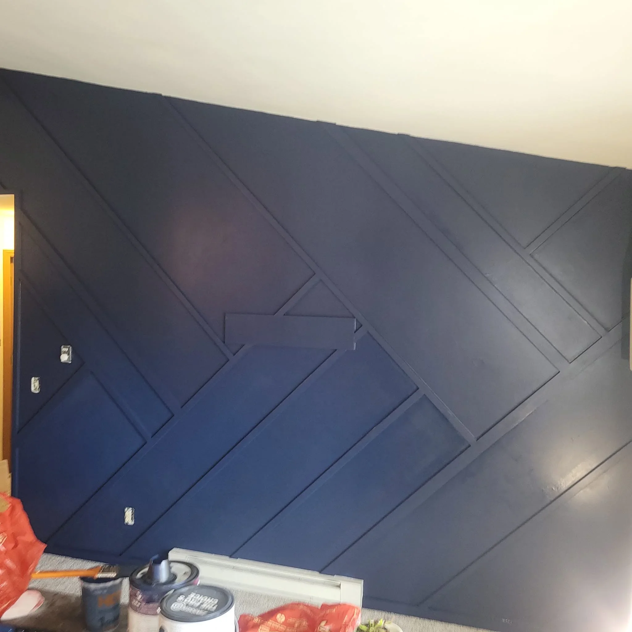 Navy blue geometric wall panels in chevron pattern with recessed lighting and drywall finish