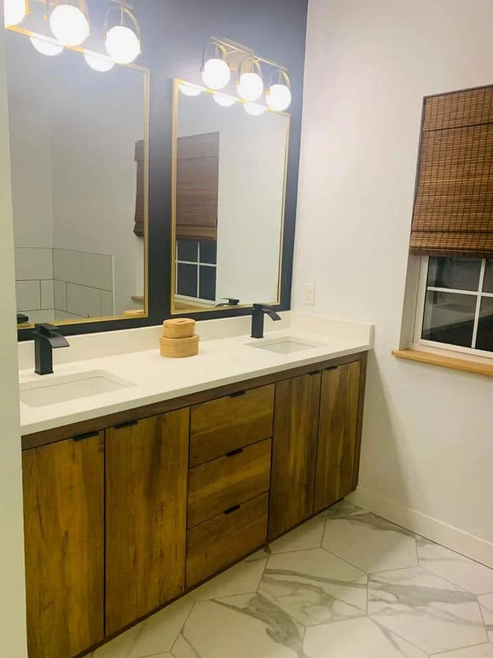 Wood vanity with white quartz countertop, dual mirrors, and brass-framed lighting fixtures