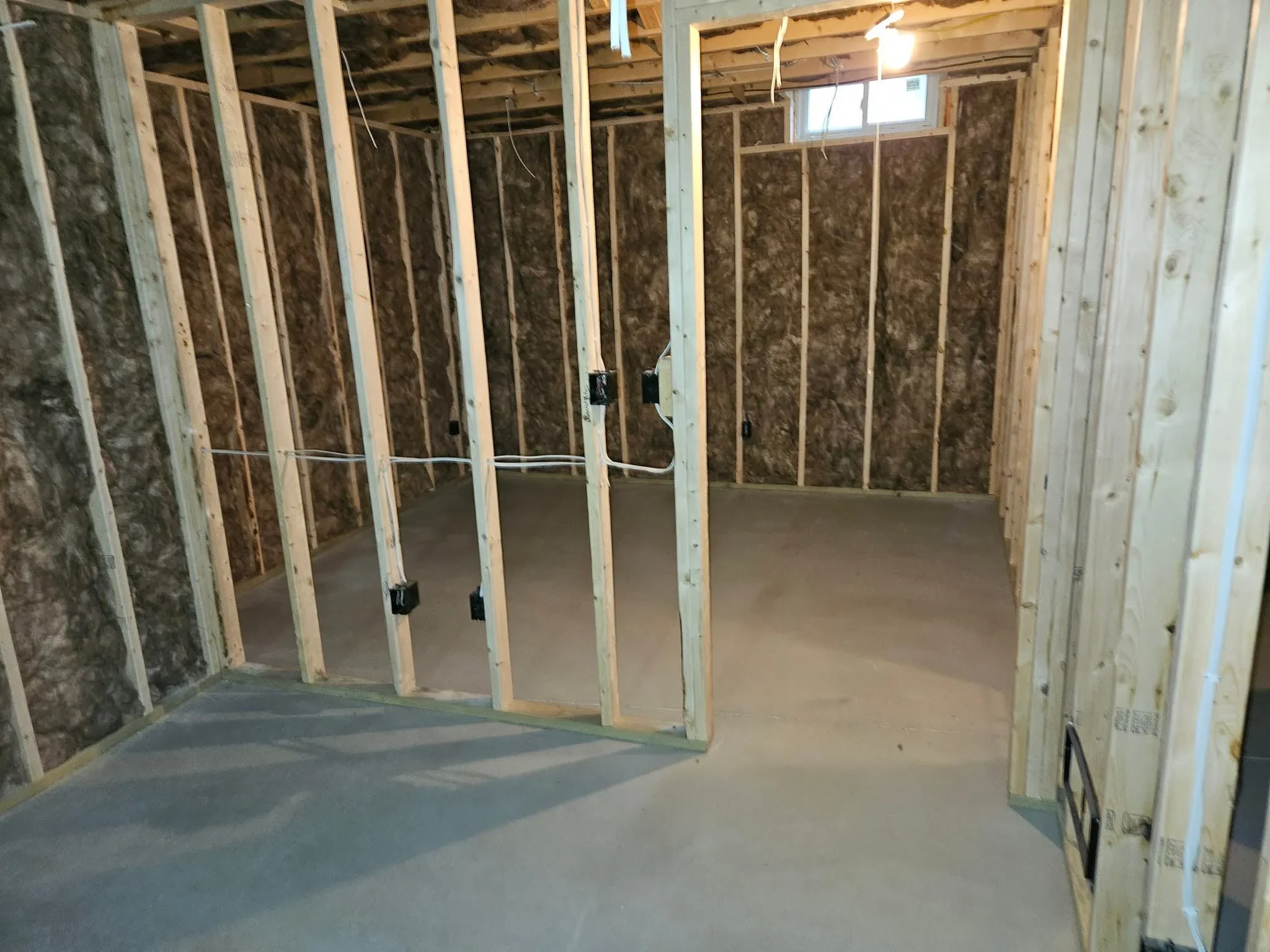 Kitchen framing with wood studs, fiberglass insulation, and electrical wiring during renovation
